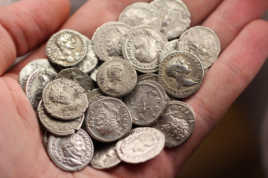 Roman silver denarius coins piled up in the palm of a hand